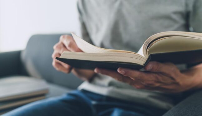 Мужчина работает или учится с книгой. Концепция бизнеса и образования