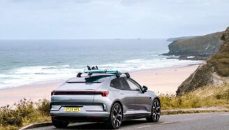 Электрический внедорожник Polestar 4, припаркованный на краю скалы со сёрфбордом на крыше
